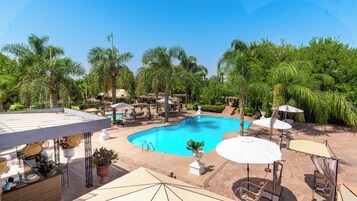 Un área de piscina con sillones de descanso, sombrillas y un mostrador de recepción.