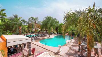 Una piscina al aire libre, sombrillas, sillones reclinables de piscina