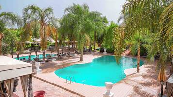 Una piscina al aire libre, sombrillas, sillones reclinables de piscina