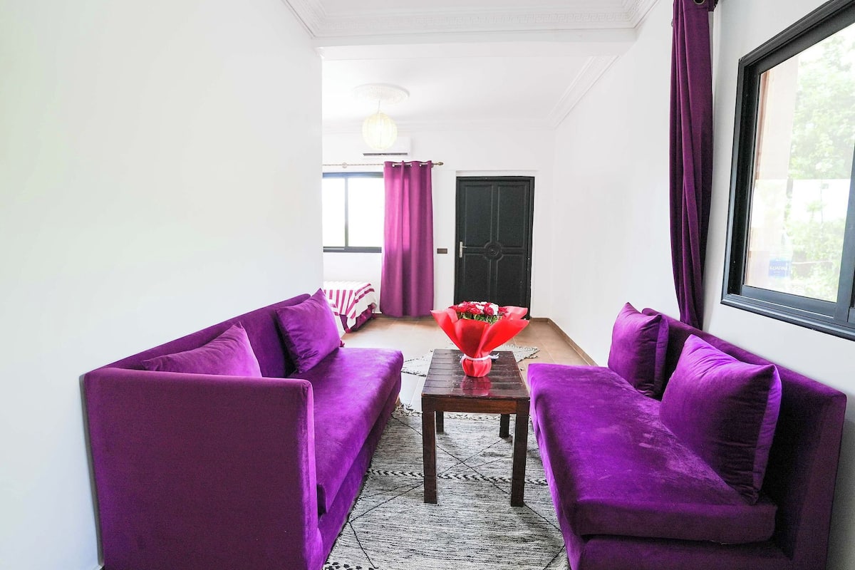 Una habitación con sofás morados, una mesita de madera y una puerta negra.