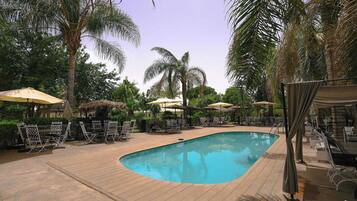Una piscina al aire libre, sombrillas, tumbonas