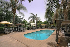 A pool area with lounge chairs and umbrellas, surrounded by palm trees. - Weedan Hotel & Spa (Oulad Hassoune)