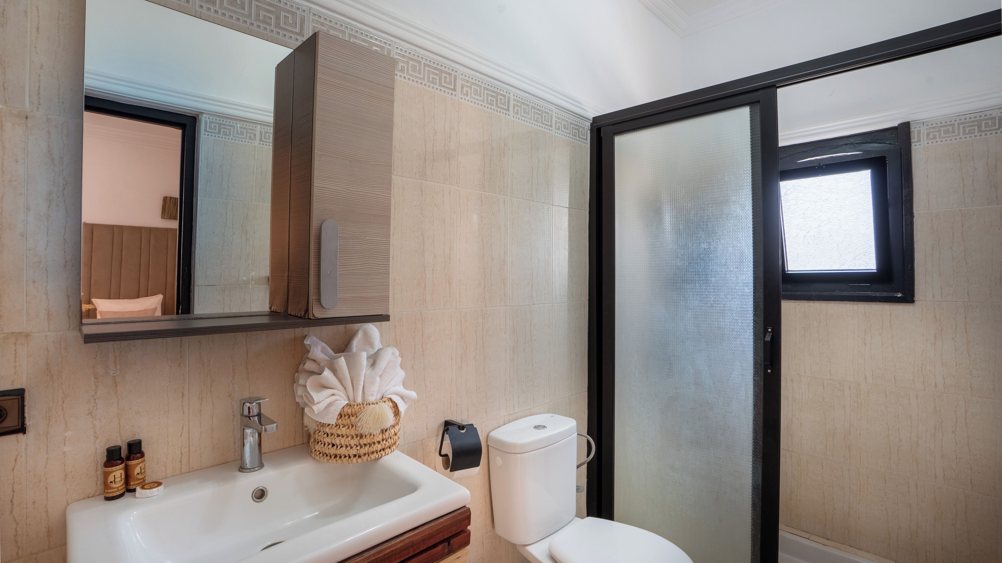 A bathroom with a sink, mirror, toilet, and a shower area.