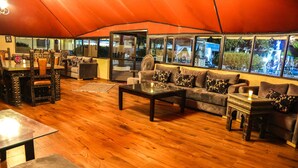 A tented room with a wooden floor, a sofa, a dining table, and chairs. - Weedan Hotel & Spa (Oulad Hassoune)