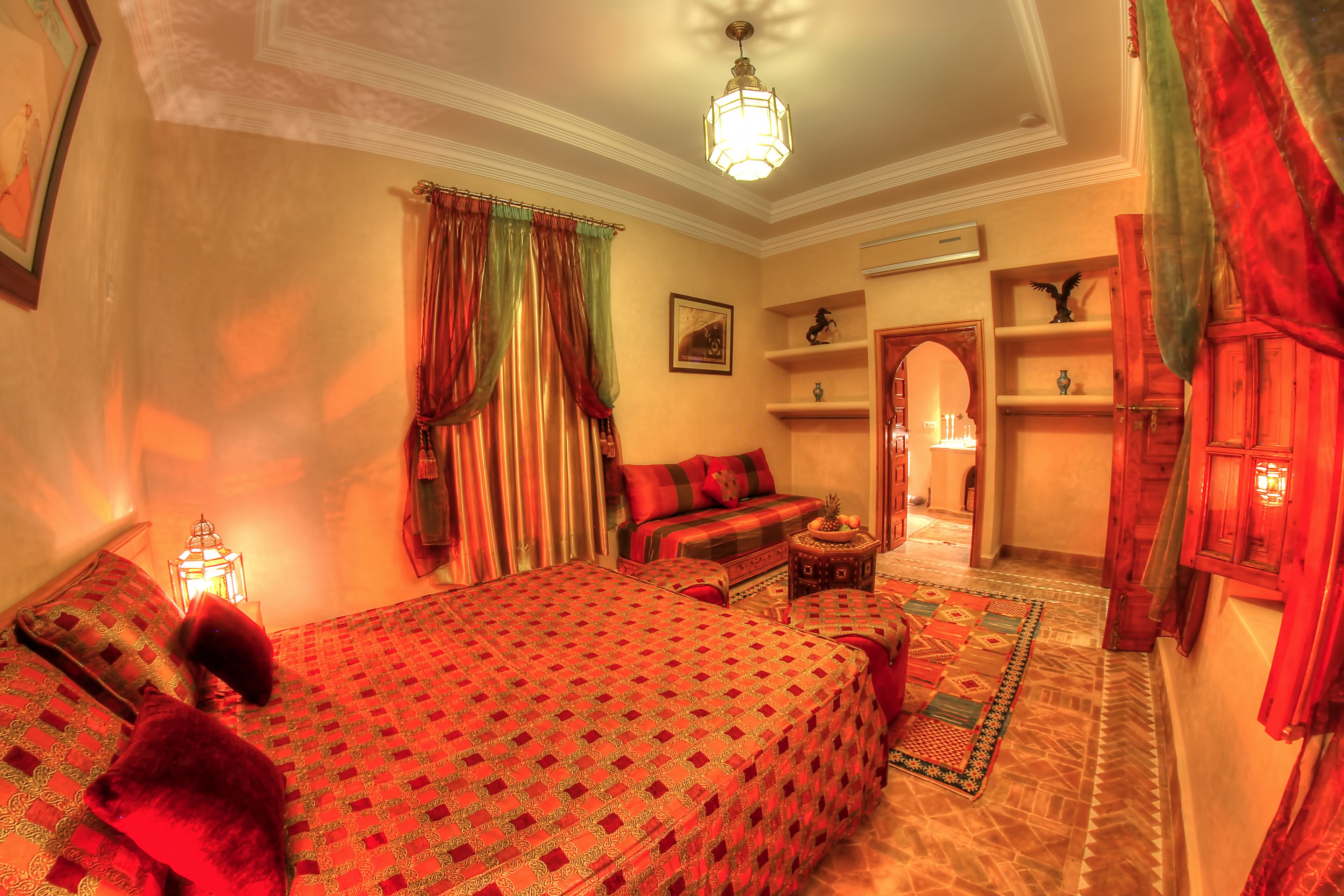 A cozy bedroom with a large bed, a nightstand, a lamp, and a view of the hallway.
