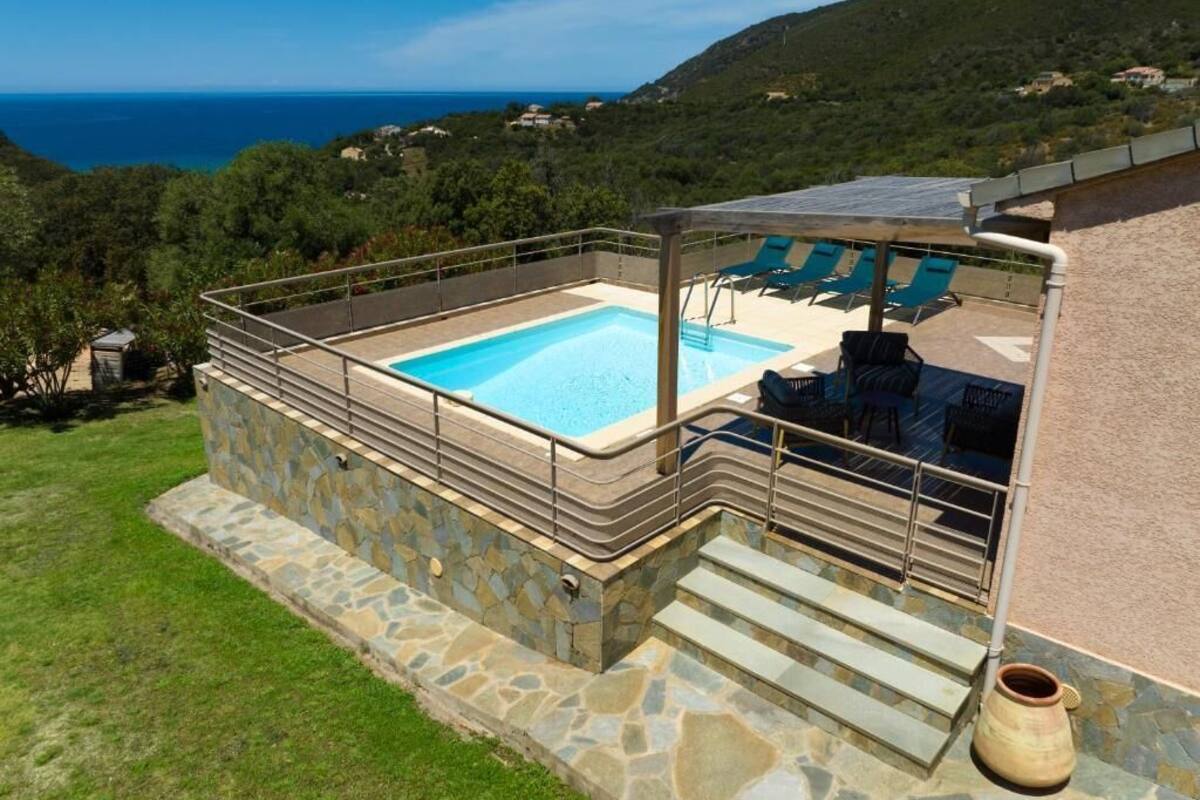 Una piscina con terraza de piedra y vista al mar.