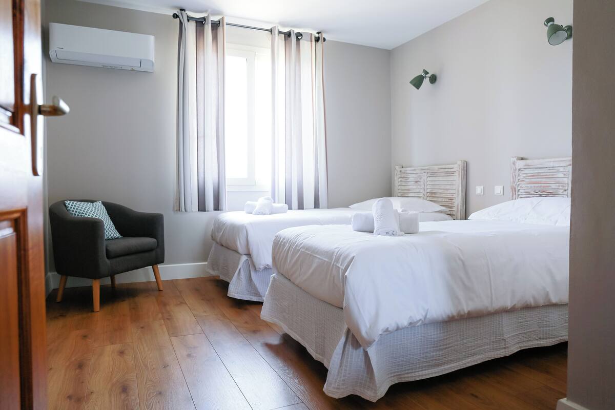 Una habitación de hotel con dos camas, una silla y un equipo de aire acondicionado.