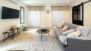 A modern living room with a sofa, coffee table, and a flat-screen TV mounted on the wall.