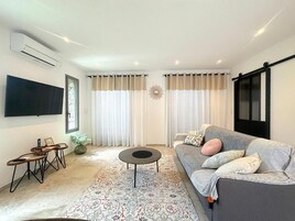 Un salon moderne avec un canapé, une table basse et un téléviseur à écran plat fixé au mur.
