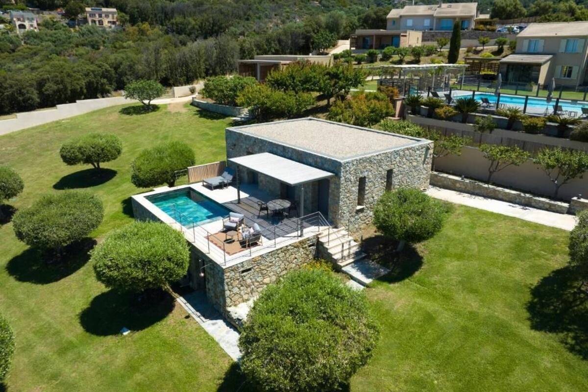 Una casa moderna con fachada de piedra, piscina y césped cuidado.
