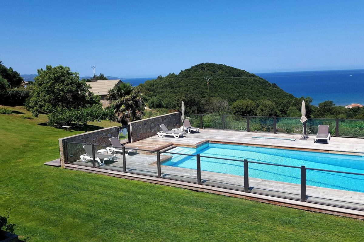 Una piscina con sillas de descanso y vistas al mar.