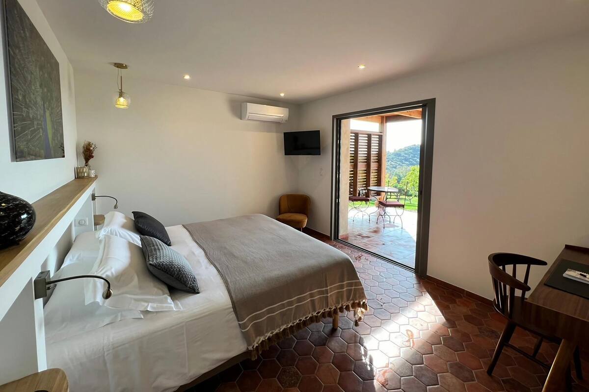 Un dormitorio con cama, escritorio y vistas al exterior.