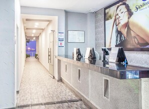A reception area with a counter, a large poster, and a view of the outside. - Hotel Santorini Kima Beach Resort (Santa Marta)