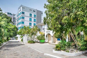 A modern building with multiple floors, surrounded by lush greenery and a paved pathway. - Hotel Santorini Kima Beach Resort (Santa Marta)