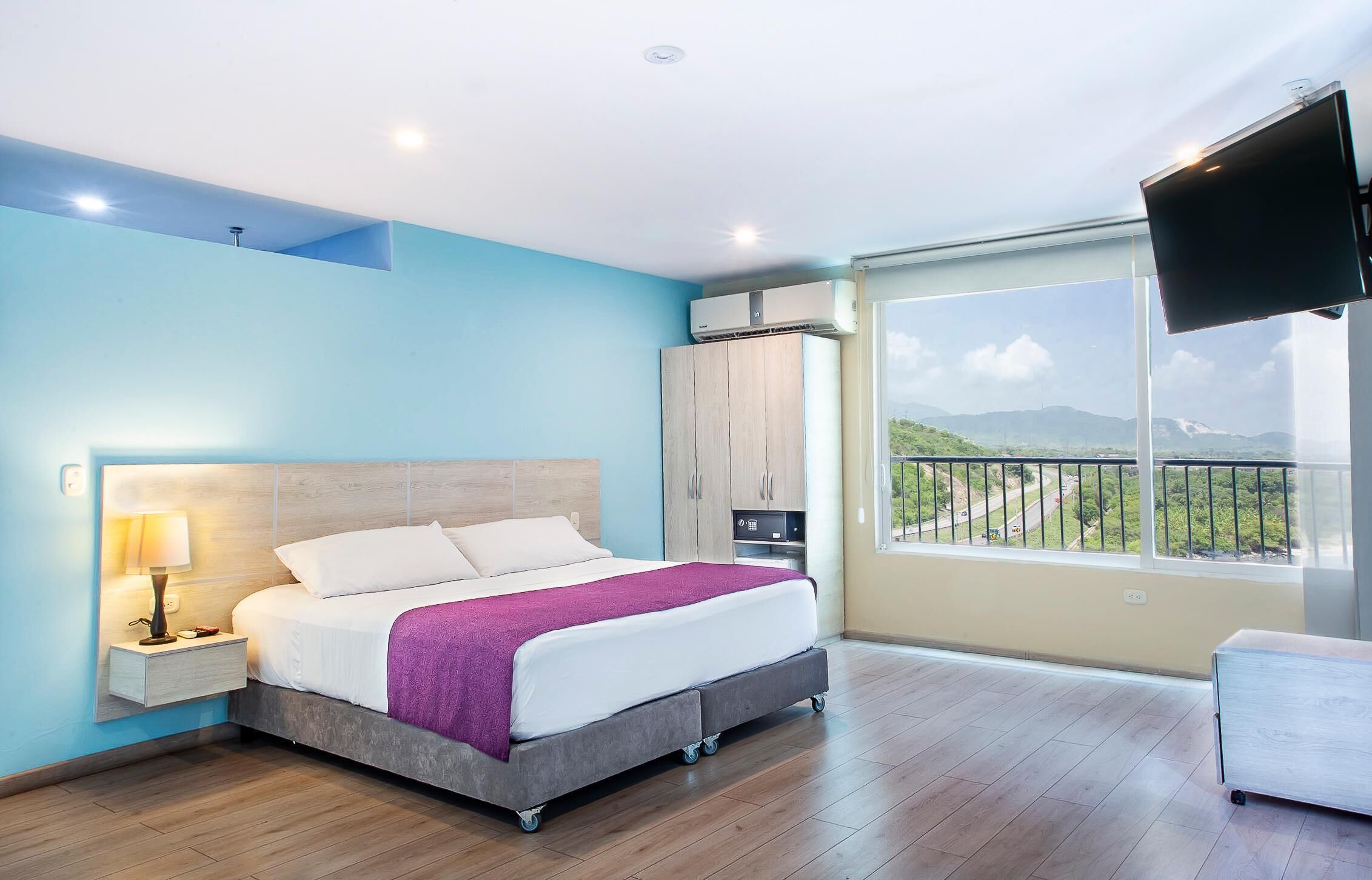 A bedroom with a bed, nightstand, and a TV mounted on the wall.