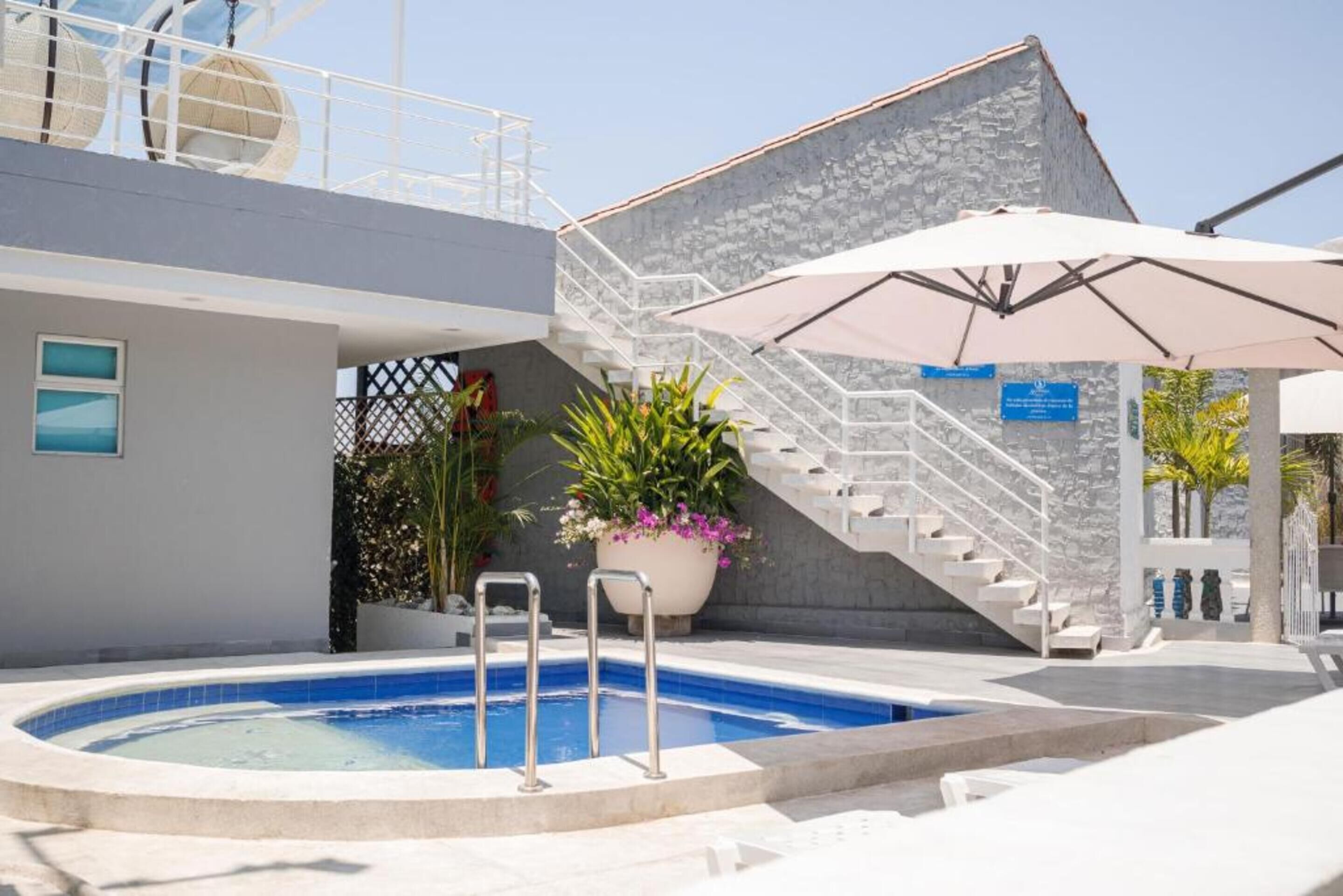 A swimming pool with a stone wall and a staircase leading to an upper level.