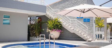 A swimming pool with a stone wall and a staircase leading to an upper level.