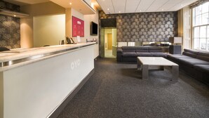 A reception area with a counter, seating, and a patterned wall.