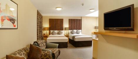 A hotel room with a sofa, two beds, a TV, and a painting on the wall.