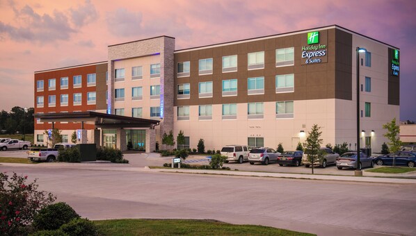 A Holiday Inn Express & Suites hotel with a modern design, multiple parking spaces, and a covered entrance.