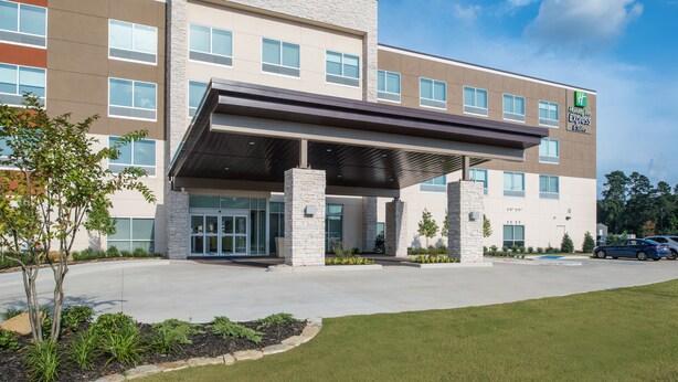 A multi-story hotel with a covered entrance, large windows, and a landscaped front yard.