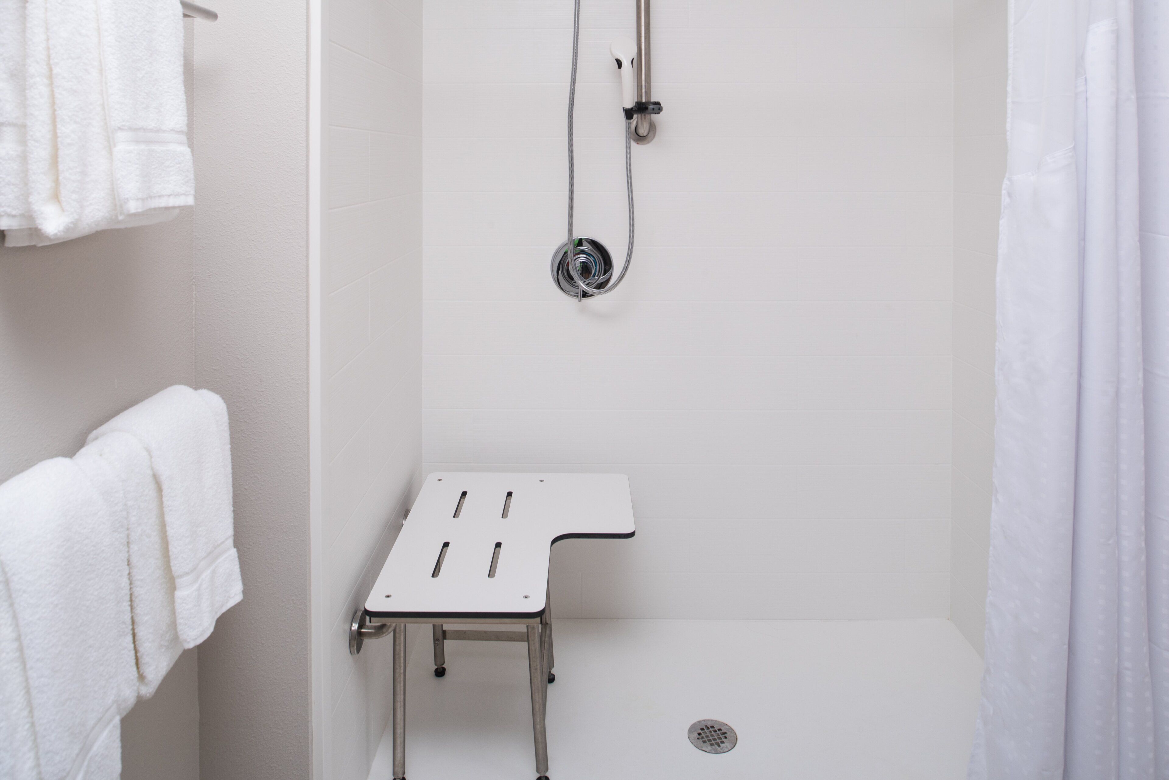 A shower area with a white showerhead, a handheld shower attachment, and a small white shelf.
