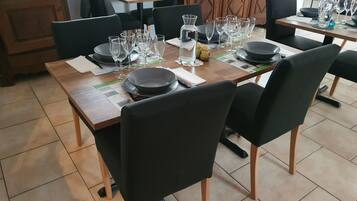 A dining area with a wooden table set for four, black chairs, and a variety of glassware and plates.