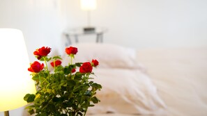 Una cama con ropa blanca y una mesita de noche con lámpara.