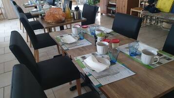 En matplats med bord som är dukade för frukost, inklusive tallrikar, koppar och en vattenkokare.
