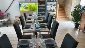 A dining table set with black plates, wine glasses, and cutlery, surrounded by black chairs.