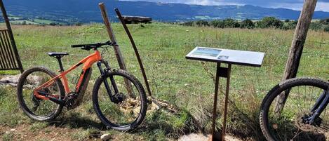 A mountain bike leaning against a wooden post with a signpost in a grassy field.