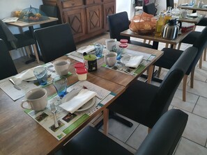 Un comedor con mesas de madera, sillas negras y una variedad de vajilla, incluyendo platos, tazas y cubiertos.