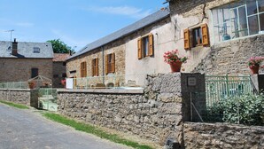 A stone building with wooden shutters, a metal gate, and potted plants.