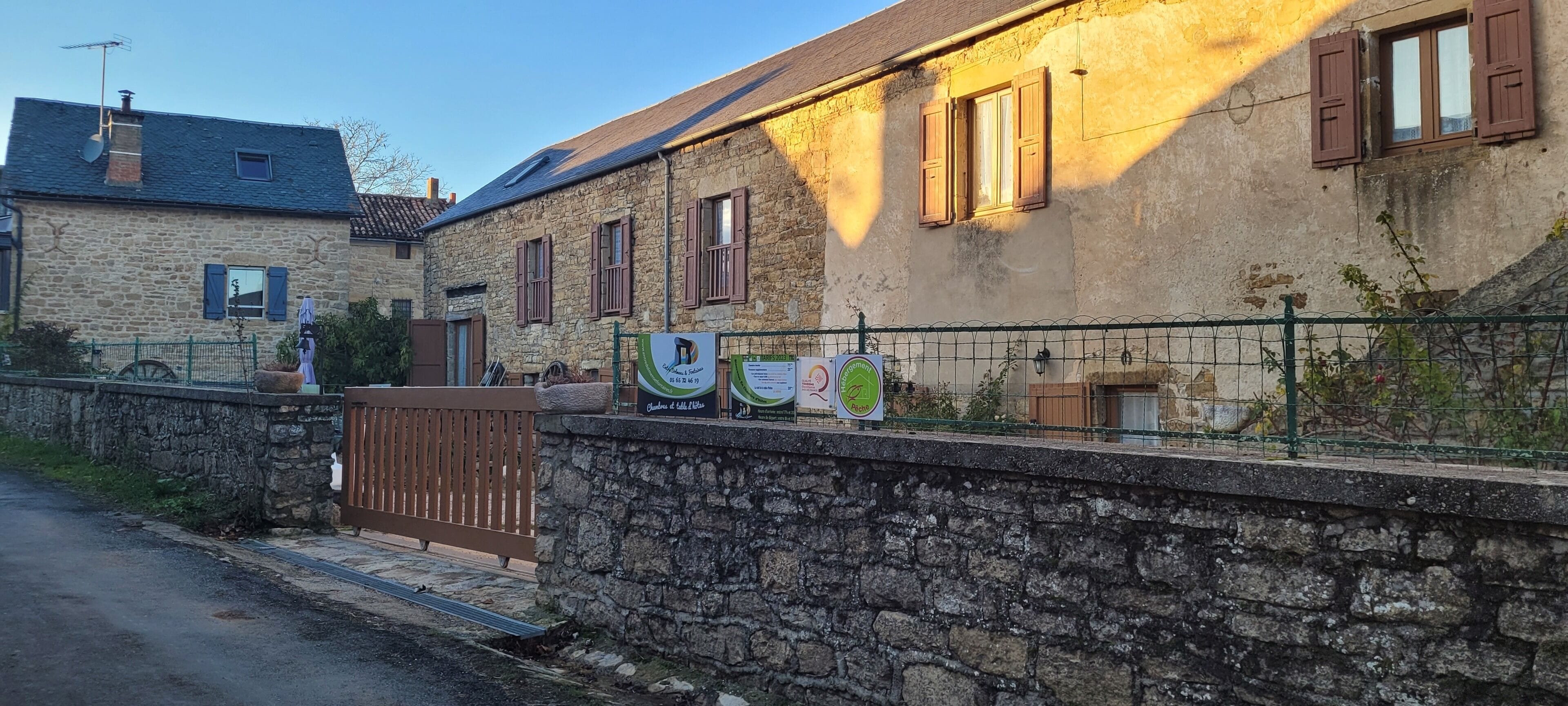 A stone building with wooden shutters, a gated entrance, and signs indicating a restaurant and a bed and breakfast.