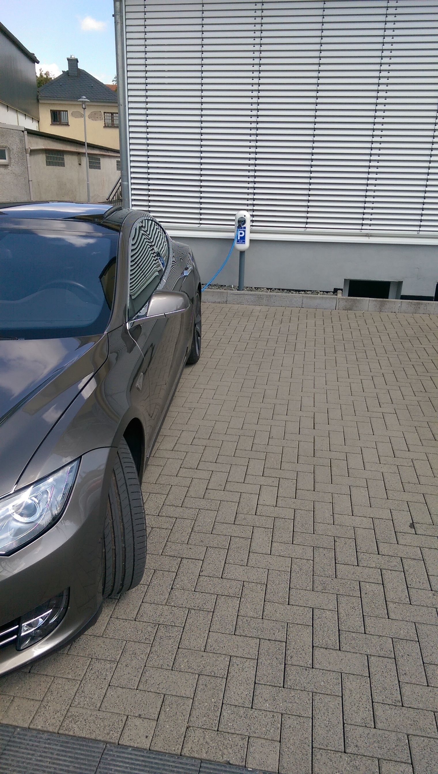 Un'auto parcheggiata in un'area asfaltata, con un edificio sullo sfondo.