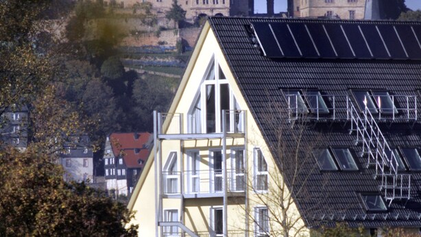 Un bâtiment historique doté d’une tour horlogée, entouré d’arbres et de bâtiments modernes.