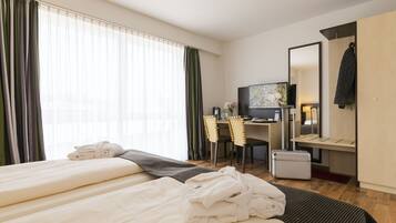 A hotel room with two beds, a desk with a computer, a TV, and a mirror.