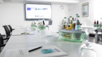 A conference room with a long table, a projector screen, and a glass bowl with bottles.