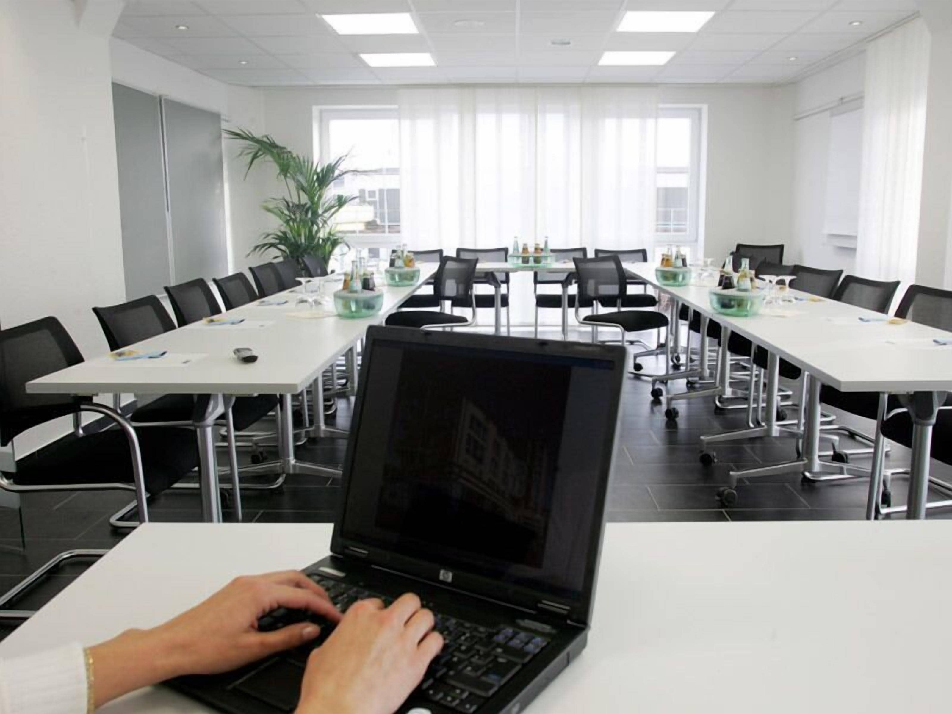 A conference room with a long table, black chairs, and a laptop on a table.