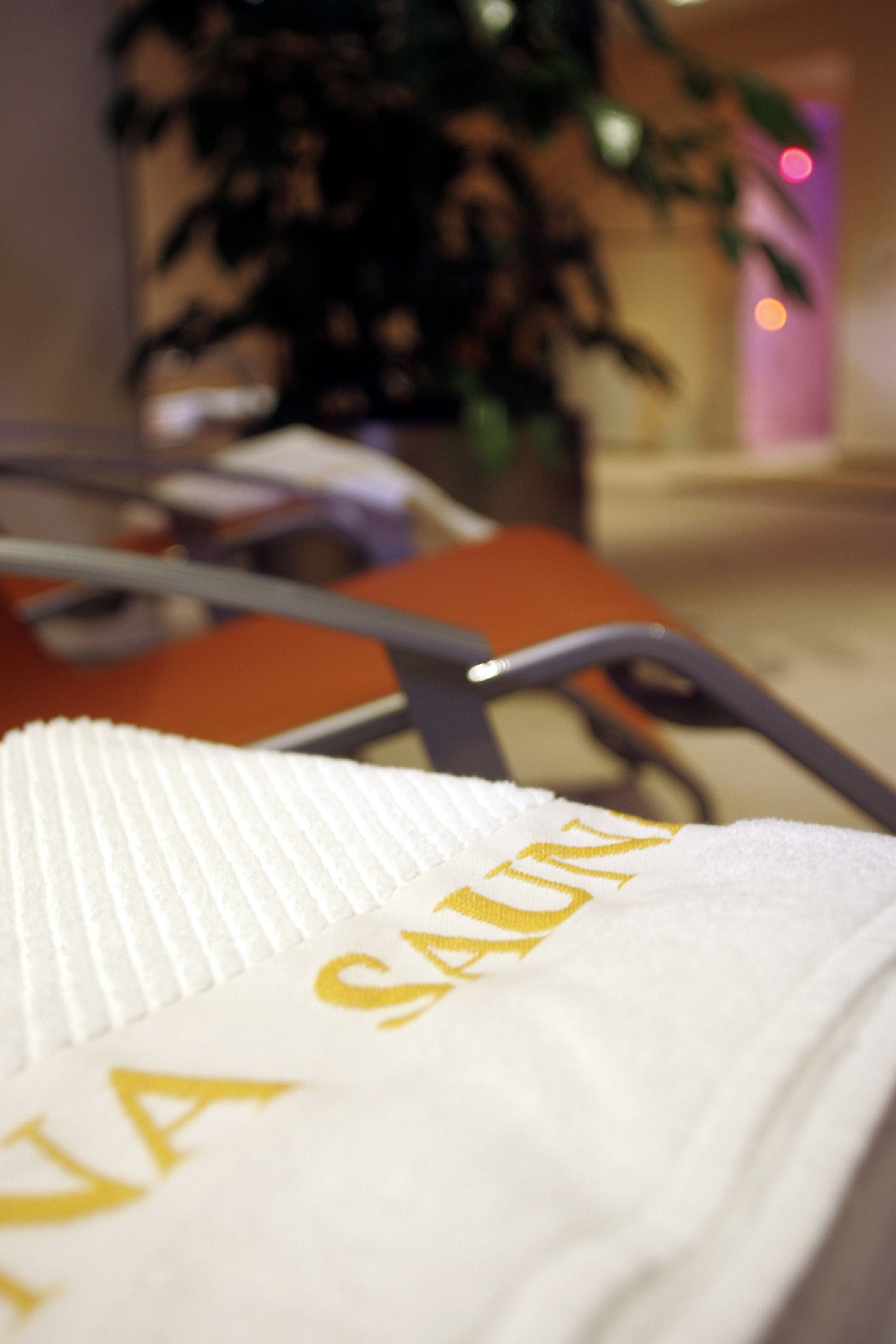A close-up of a white towel with the text "SAUNA" in gold lettering.