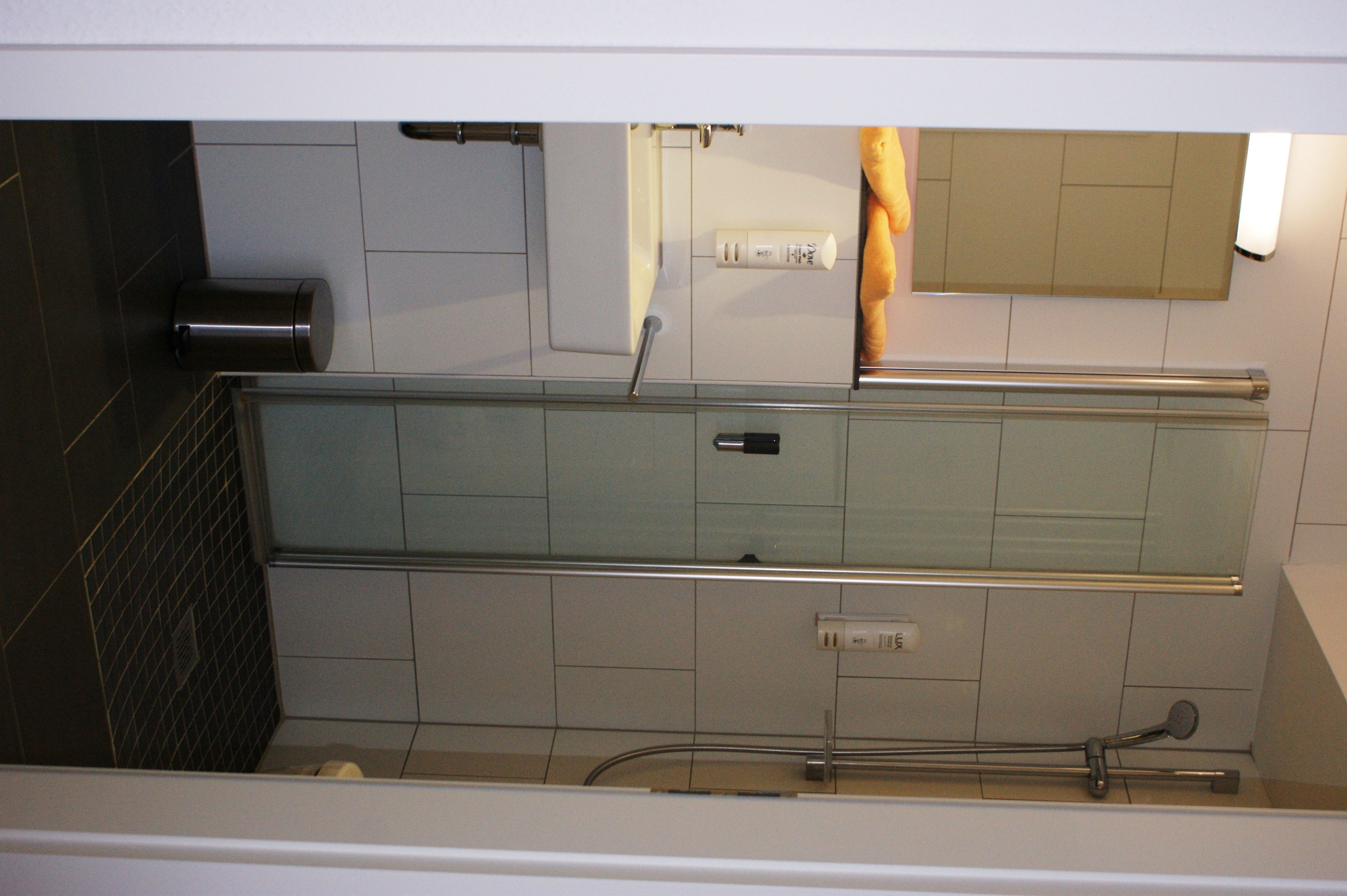 A bathroom with a glass shower enclosure, a towel rack, and a toilet.