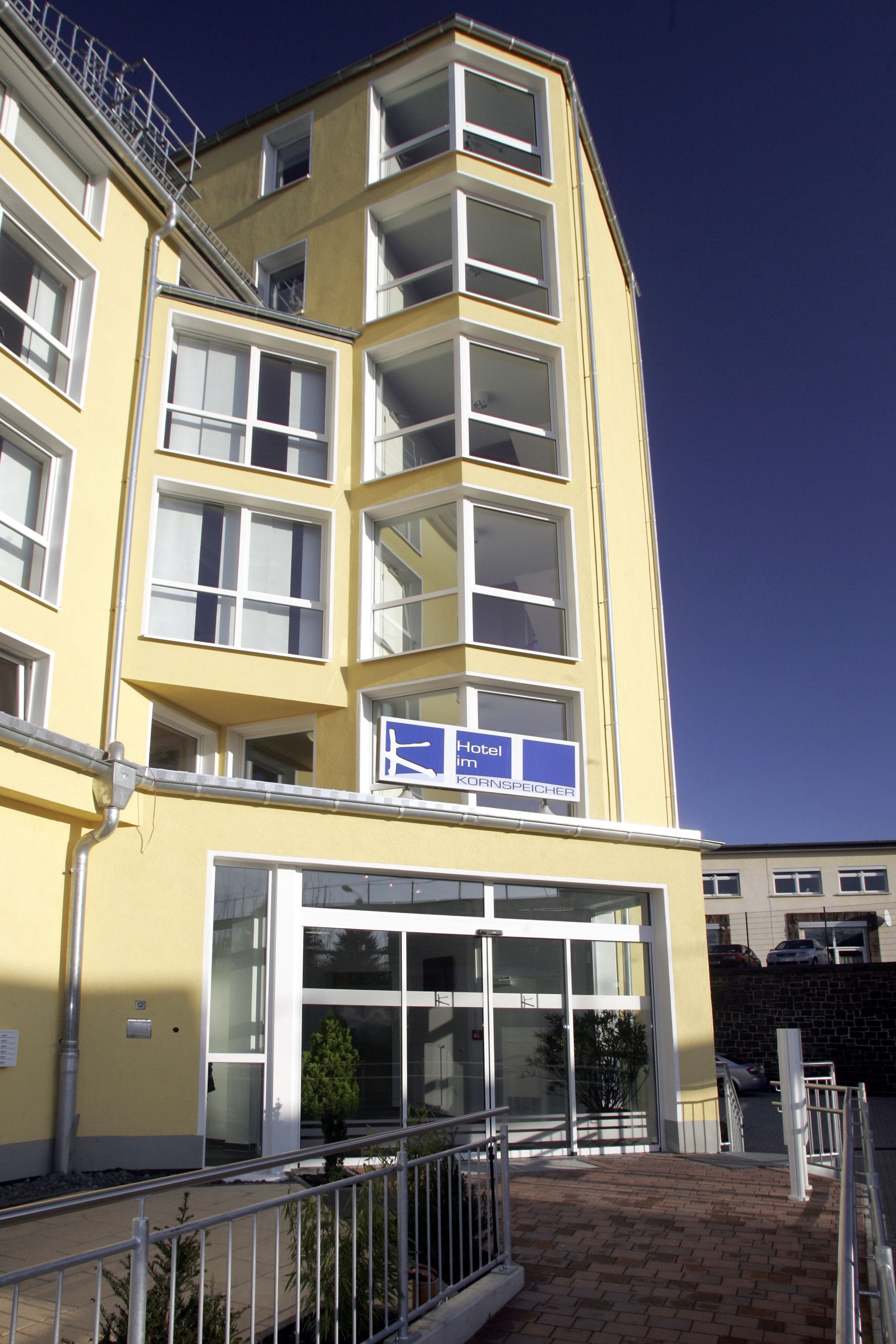 A yellow hotel building with multiple floors, large windows, and a sign indicating it is a hotel.