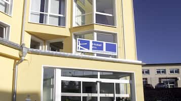 A yellow hotel building with multiple floors, large windows, and a sign indicating it is a hotel.