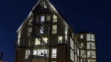 A multi-story building with a prominent fire escape, large windows, and a balcony.