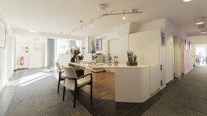 Un hall d’hôtel moderne doté d’un comptoir d’accueil, d’un espace salon et d’une grande fenêtre laissant entrer la lumière naturelle.