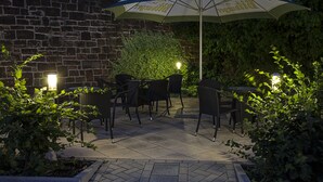 Une terrasse extérieure avec des murs en briques, un grand parasol et du mobilier d’extérieur.