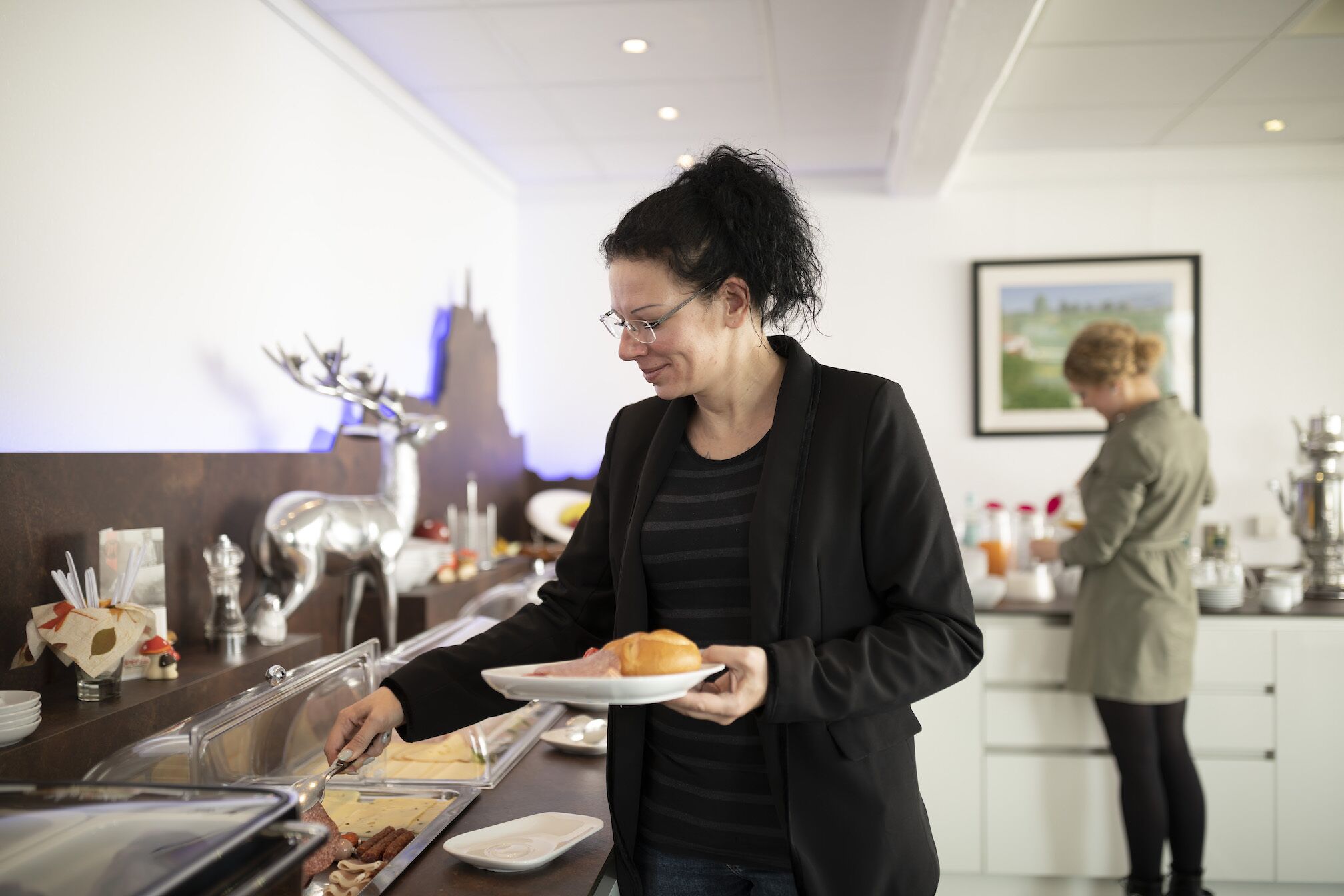 A buffet area with various food items and a person serving themselves.