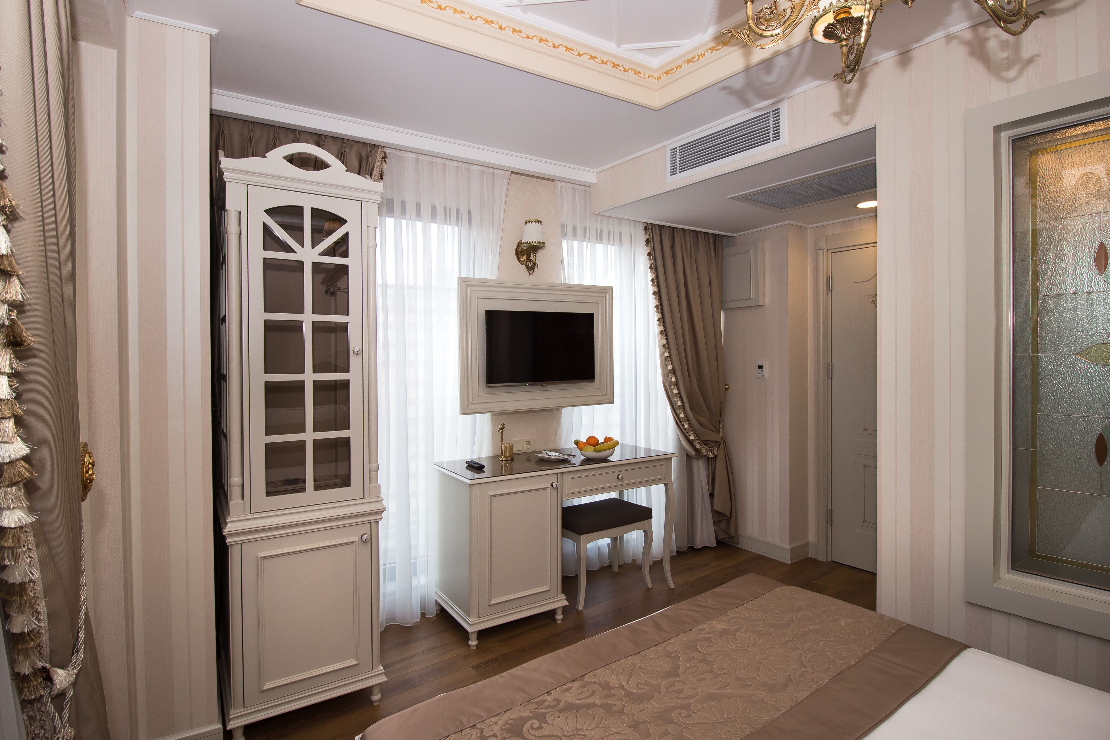 Una habitación con un escritorio blanco, televisor y puerta.