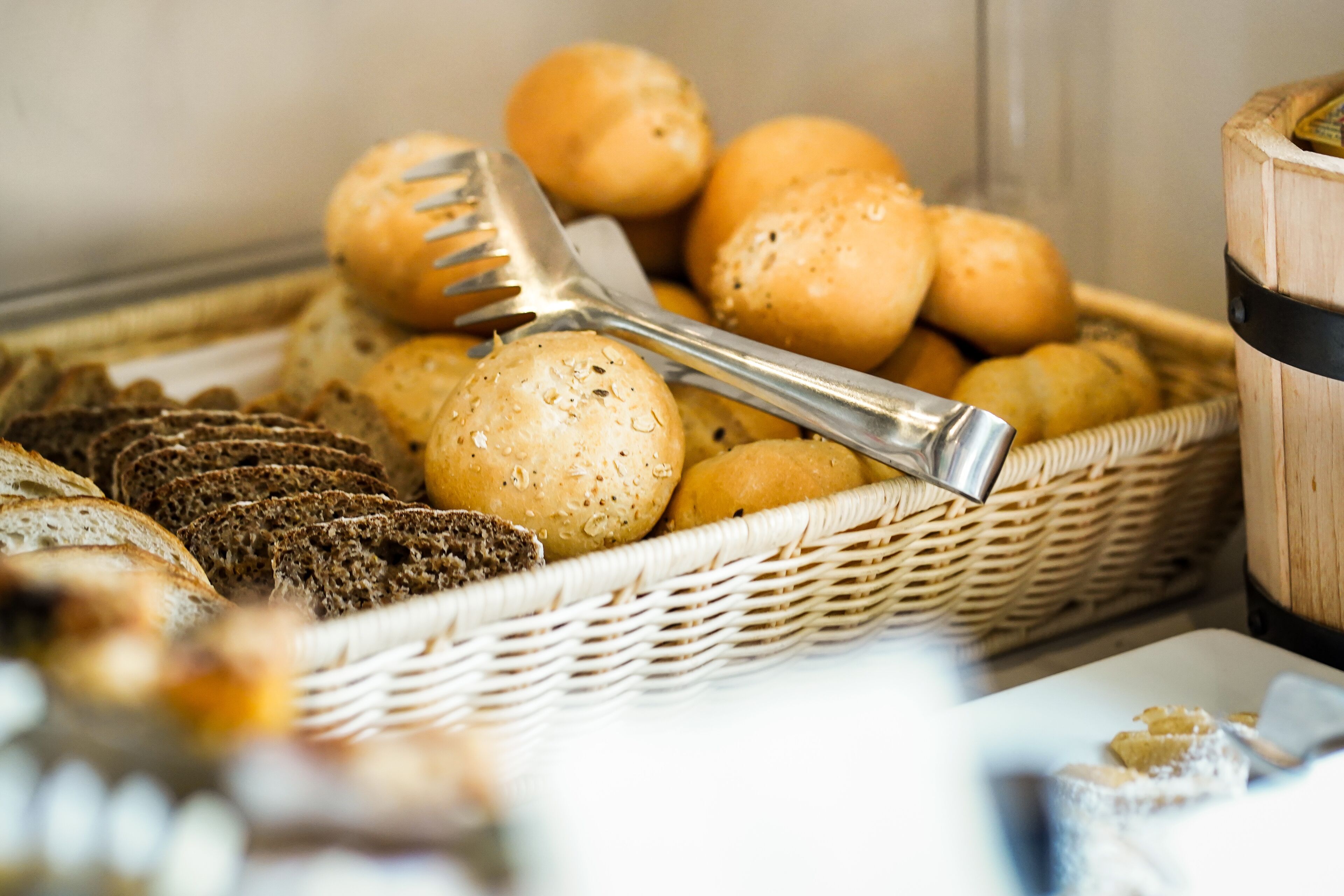 A basket of bread and rolls, a knife, and a wooden container.