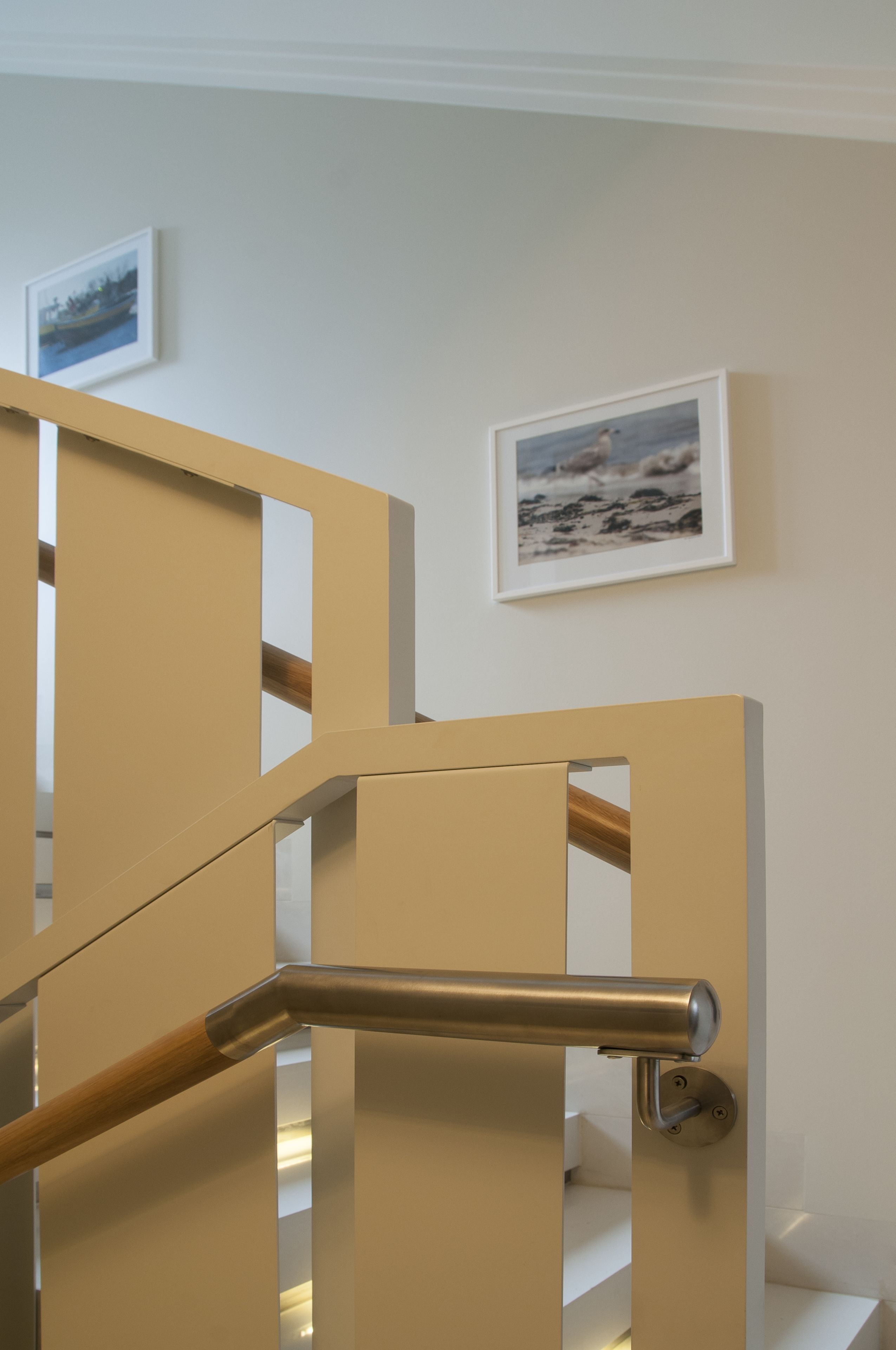 A modern staircase with a metal handrail and beige walls.